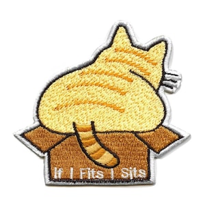 May include: Embroidered patch featuring a yellow tabby cat's rear end in a brown cardboard box. The patch has a white border and the text "If It Fits I Sits" in white. The cat's fur has orange stripes.