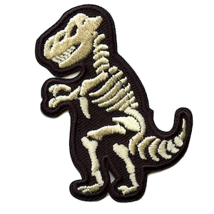 May include: A brown embroidered patch depicting a dinosaur skeleton. The dinosaur is standing on its hind legs with its tail curled around its body. The skeleton is outlined in white thread.