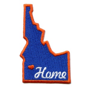 Op de afbeelding: Een geborduurde patch in de vorm van de staat Idaho met een oranje rand. De patch is blauw met een wit hart en het woord "Home" in witte cursieve letters.
