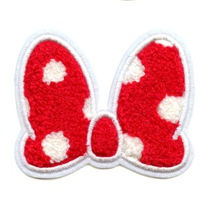May include: Red and white polka dot bow with a white outline. The bow is made of a fuzzy material.