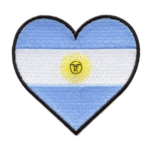 May include: A heart-shaped patch with the flag of Argentina. The flag is blue and white with a yellow sun in the center.
