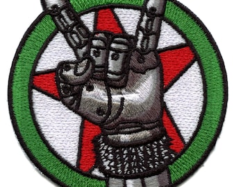 May include: A green circle with a red star inside. A silver hand with a black glove is making the rock and roll hand gesture. The hand is in front of the star.
