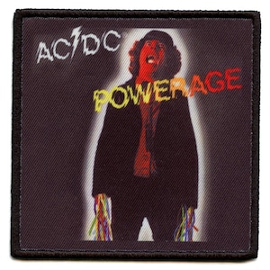 May include: Square patch featuring the AC/DC logo and the word "POWERAGE" in a stylized font. The image depicts a person with a red face and black suit. The patch has a black border and a dark background.