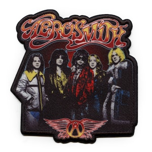 Könnte beinhalten: Ein schwarzer und weißer gestickter Patch mit dem Bandnamen "Aerosmith" in einer stilisierten Schriftart. Der Patch zeigt eine Gruppe von fünf Personen, darunter Steven Tyler, Joe Perry, Brad Whitford, Tom Hamilton und Joey Kramer. Der Patch enthält auch das ikonische geflügelte Logo der Band.