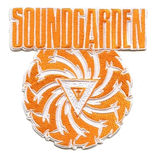 May include: Orange and white embroidered patch featuring the band name "SOUNDGARDEN" in large letters at the top and a swirling, stylized design with a triangle in the centre.