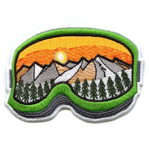 Puede incluir: Parche bordado de unas gafas de esquí verdes con una escena de montaña en su interior. La escena muestra una puesta de sol con tonos naranja y amarillo, montañas cubiertas de nieve y un bosque de árboles verdes.