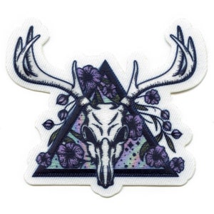 May include: A white deer skull with antlers is surrounded by purple flowers and leaves inside a black triangle with a colorful, iridescent background.
