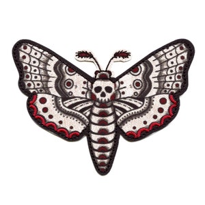 May include: Embroidered moth patch with a skull design on the body. The moth has white wings with black and red accents. The patch has a black border.