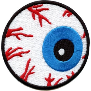 May include: A white eye with red blood vessels and a blue iris. The eye is surrounded by a black circle.