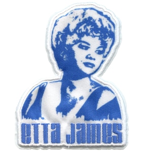 May include: A blue and white embroidered iron-on patch featuring a portrait of Etta James. The patch has a white border and the text "Etta James" in blue.