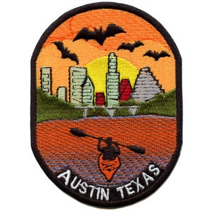 May include: Oval patch featuring an Austin, Texas, design. The patch depicts a sunset over a cityscape with bats, a kayaker, and the text "AUSTIN TEXAS". The patch has an orange, yellow, green, and brown color scheme.