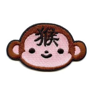 May include: Embroidered brown monkey face patch with pink cheeks and the Japanese character for monkey, "猿", on its forehead.