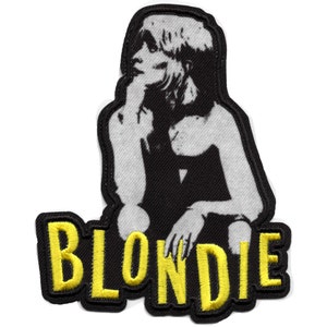 Puede incluir: Parche bordado en blanco y negro de una mujer con cabello rubio, vistiendo un vestido negro, con la palabra "BLONDIE" en bordado amarillo debajo.