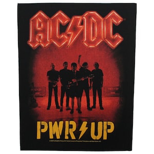 Op de afbeelding: Een zwart en rode patch met het logo van de band AC/DC in rode neonlichten. De bandleden zijn gesilhouetteerd voor het logo. De tekst "PWR/UP" is in geel met een bliksem. De tekst "2020  Labelscape Press  R.V. Under License to  Purpose Productions, LLC.  Rights, LLC." staat onderaan de patch.