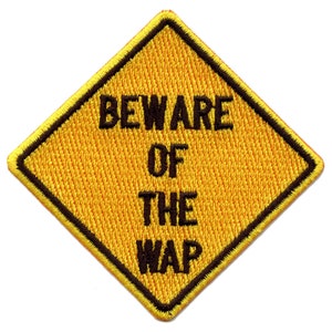 Può includere: Un cartello di avvertimento giallo a forma di diamante con bordo nero. Il cartello recita "BEWARE OF THE WAP" in lettere nere.