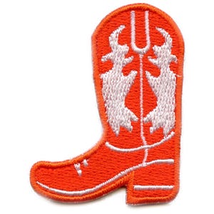 May include: Orange cowboy boot embroidered patch with white stitching. The boot has a pointed toe and a decorative design on the top.