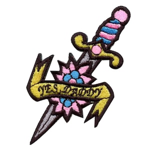 May include: An embroidered iron-on patch featuring a dagger with a pink and blue striped handle, a pink flower with blue accents, and a yellow banner with the text "YES DADDY".