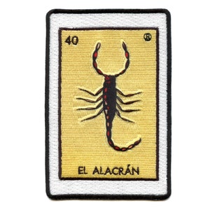 Könnte beinhalten: Ein gestickter Patch mit einem Skorpion in der Mitte auf gelbem und weißem Hintergrund. Der Skorpion ist schwarz mit roten Akzenten. Der Text "EL ALACRÁN" ist unter dem Skorpion gedruckt. Die Nummer "40" ist in der oberen linken Ecke des Patches gedruckt.