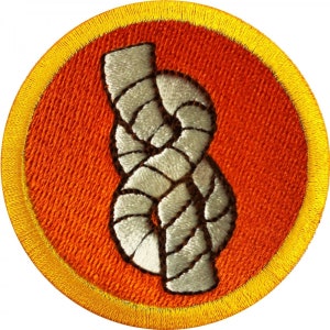 Op de afbeelding: Een ronde, oranje geborduurde patch met een gele rand. De patch toont een wit touw dat in een knoop is geknoopt.