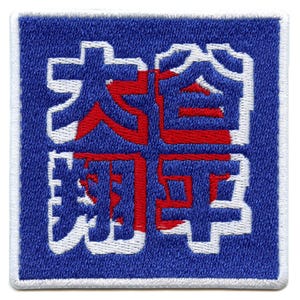 Può includere: Toppa quadrata blu ricamata con caratteri giapponesi bianchi e rossi. La toppa ha un bordo bianco e un aspetto strutturato. I caratteri giapponesi sono in un carattere audace e stilizzato.