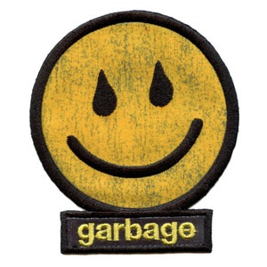 May include: Yellow smiley face patch with black outline and teardrop eyes. The patch has a distressed, vintage look. Below the smiley face is a black rectangular patch with the word "garbage" in yellow lettering.