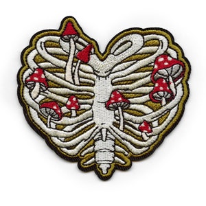 Puede incluir: Parche bordado en forma de corazón, con un diseño de caja torácica y setas rojas y blancas. El parche tiene un borde negro y detalles dorados. Ideal para personalizar chaquetas, bolsos u otros artículos de tela.