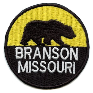 Puede incluir: Un parche redondo bordado en negro y amarillo con una silueta de oso negro y el texto "Branson Missouri" en blanco.