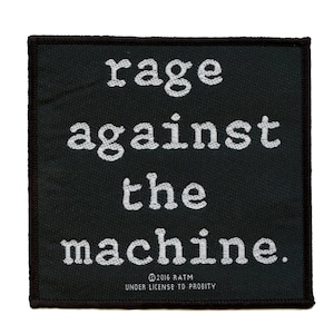 以下が含まれることがあります： 黒と白の刺繍パッチで、「rage against the machine.」というテキストが書かれています。テキストはタイプライターのフォントです。パッチは黒い縁取りがあり、布製です。