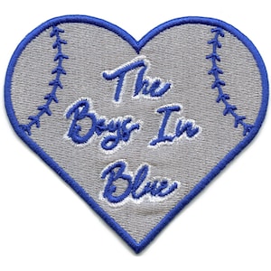 Può includere: Toppa a forma di cuore a tema baseball. La toppa è grigia con cuciture blu sui bordi e sui lati, che ricordano una palla da baseball. Le parole "The Boys In Blue" sono ricamate in blu.