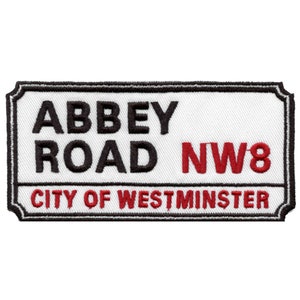 May include: White and black Abbey Road street sign with red lettering. The sign reads "Abbey Road NW8 City of Westminster".