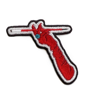 Può includere: Toppa ricamata rossa di una mano che tiene un bastone bianco con una striscia rossa. La mano indossa un anello blu.