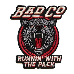 May include: A black and red embroidered patch with a wolf's head in the center. The wolf has red eyes and an open mouth. The text "BAD CO" is above the wolf and "RUNNIN' WITH THE PACK" is below the wolf.