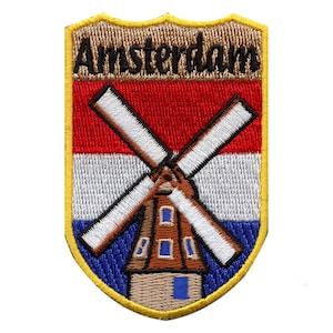 May include: An embroidered patch with a brown windmill and the Dutch flag. The patch is shaped like a shield and has the word "Amsterdam" written on it in brown letters.