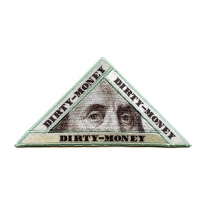 May include: A triangular patch with a green border and a white interior. The patch features a close-up of Benjamin Franklin's face and the text "DIRTY-MONEY" repeated three times around the border.