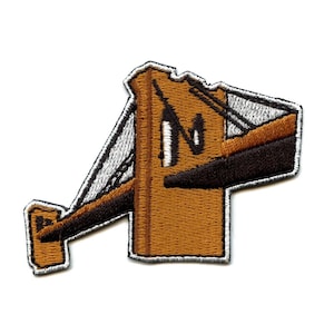 May include: An embroidered patch featuring a brown and black illustration of the Golden Gate Bridge in San Francisco, California. The bridge is outlined in white thread.