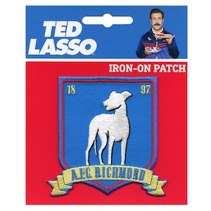 Puede incluir: Un parche termoadhesivo de Ted Lasso con un escudo azul, un galgo blanco, los números 18 y 97 en dorado y una cinta dorada en la parte inferior con el texto A.F.C. RICHMOND. El empaque incluye una imagen de Ted Lasso sosteniendo una taza de té.