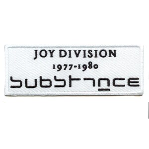 Könnte beinhalten: Weißer rechteckiger Patch mit schwarzem gesticktem Text, der "JOY DIVISION 1977-1980 Substance" lautet.