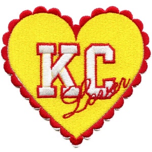 Puede incluir: Un parche amarillo en forma de corazón con un "KC" bordado en blanco y un "Love" bordado en rojo en letra cursiva.