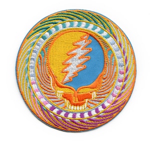May include: Circular embroidered patch with a Steal Your Face design. The patch has a blue centre, yellow and orange details, and a white lightning bolt. The outer border features teal, white, pink, and purple detailing.
