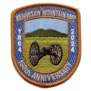 May include: A blue and orange embroidered patch with the text "Kennesaw Mountain NBP 1864-2024 160th Anniversary". The patch features a cannon and a mountain.