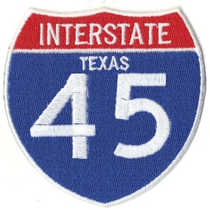 May include: A blue and red interstate highway sign with white text. The sign reads "Interstate Texas 45".