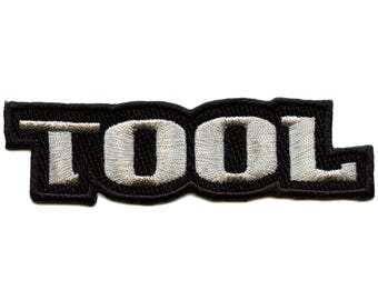 Könnte beinhalten: Ein gestickter schwarzer und weißer Aufnäher mit dem Wort "TOOL" in weißen Buchstaben.