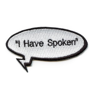 May include: A white embroidered patch with a black outline in the shape of a speech bubble. The text inside the speech bubble reads "I Have Spoken".
