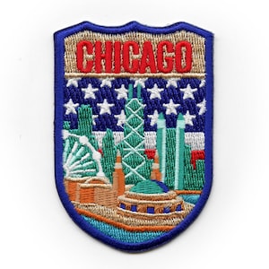 Op de afbeelding: Geborduurde patch met een Amerikaanse vlag achtergrond in blauw, wit en rood. De patch toont een skyline van Chicago met het woord "CHICAGO" in rode letters.
