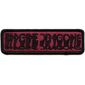 May include: Black embroidered patch with the words "Imagine Dragons" on a burgundy background.