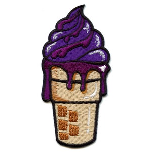 Könnte beinhalten: Gestickter Aufnäher in Form eines Eisbechers mit lila und weißem Eis. Das Eis tropft vom Becher.