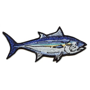 May include: An embroidered iron-on patch of a blue and silver fish with a yellow stripe. The fish is facing right and has a detailed design.