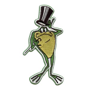 May include: Green frog wearing a black top hat with a white band, standing with one leg raised and a cane in its hand. The frog has a yellow body and white eyes.