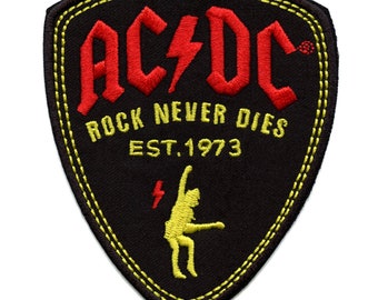 May include: Black and yellow embroidered patch with the text "AC/DC Rock Never Dies Est. 1973" and a yellow silhouette of a person playing guitar.
