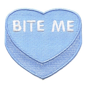 May include: A light blue heart-shaped candy with the text "BITE ME" in white.